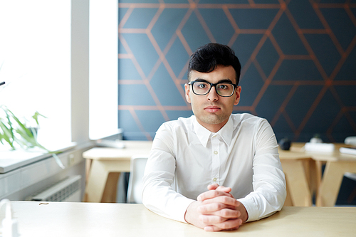 Businessman in eyeglasses and white shirt sitting by desk