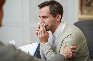 Man addicted to alcohol wiping tears during conversation with psychologist