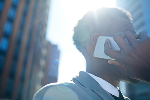 Young modern businessman holding smartphone by his ear and calling