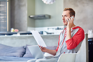 Home-office economist with financial paper speaking by smartphone