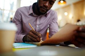 African designer making notes or drawing sketch in notepad