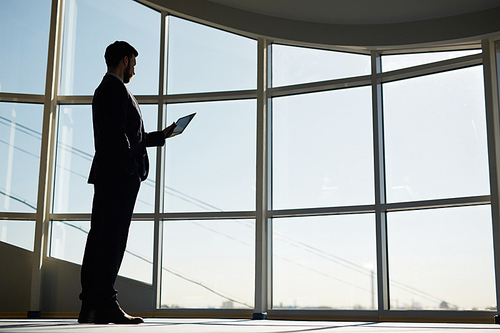 Modern businessman with touchpad networking inside office building