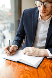 Busy financier making notes in notebook while planning working schedule