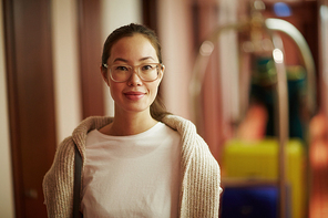 Portrait of smiling Asian woman standing in hotel hall with bags 