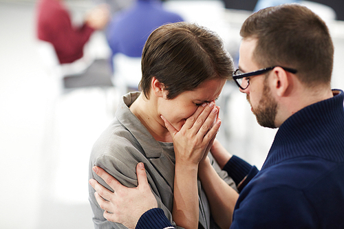 Helpful man reassuring upset woman at course of psychological support