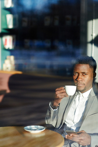 Confident businesman sitting in coffee-shop on sunny morning