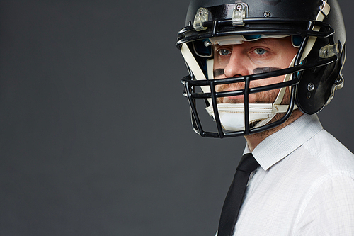 Closeup portrait of confident middle aged businessman with army paint on his face wearing helmet and  away against grey background