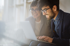 Portrait of two successful businesspeople checking statistics information, both smiling joyfully while looking at laptop screen