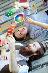 Young man and woman lying on the floor and discussing color swatches