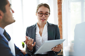 Confident financier with tablet explaining her colleague online data