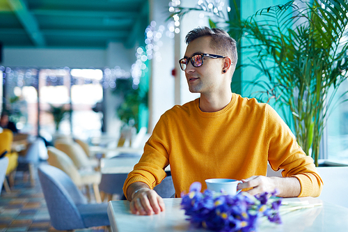 Portrait of young man in cafe waiting for date with bouquet of irises