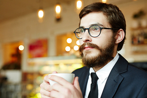 Pensive businessman with cup of tea contemplating at break in cafe