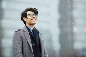 Happy man in eyeglasses, suit and coat enjoying winter day