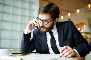 Smart man phoning about curious vacancy in newspaper while seeking for job