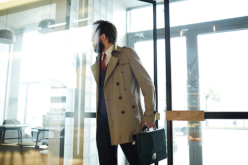 Busy professional with briefcase entering modern cafe to buy hot drink