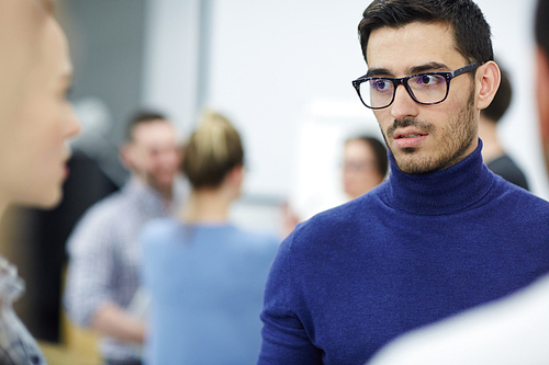 Young employee listening to one of colleagues during talk