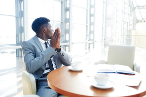 Inspired businesman sitting by table at coffee-break