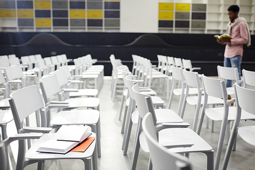 Rows of white plastic chairs and student preparing for exama on background