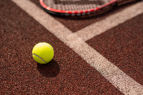 Yellow tennis ball by white line of sports playground and its shadow