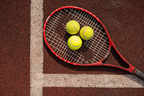 Top view of three tennis balls on racket by white line of sports playground