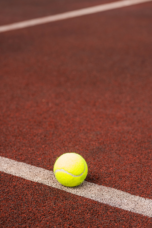 Single yellow ball for playing tennis on white line in the center of stadium or court