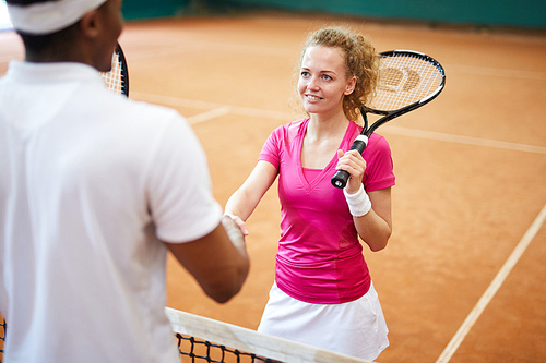 Female tennis player handshaking with her African playmate before or after game at court