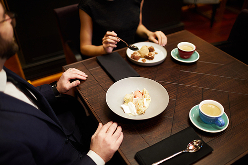 Young man and his girlfriend having dessert and aromatic coffee after dinner in restaurant