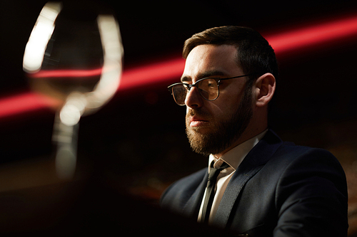 Bearded businessman in formalwear and eyeglasses spending time or working in luxurious restaurant