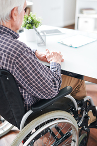 mature lonely handicapped man in . sitting by desk in office or hospital while waiting for someone