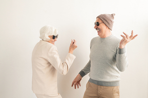 Happy casual senior couple in sunglasses having fun and dancing in isolation over white background