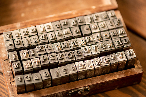 Set of special bars with latin letters and arabic numbers in open wooden box that are used to make prints on soft surface
