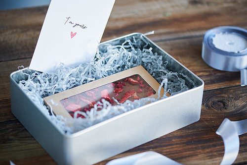 Open giftbox with present and greeting card for sweetheart prepared for valentine day