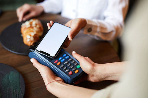 Young contemporary buyer using contactless payment system to pay for food and drink in cafe or restaurant