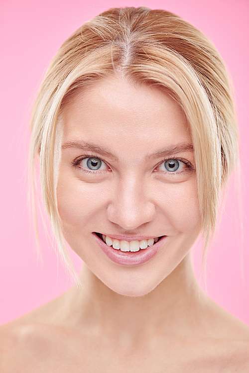 Young beautiful smiling woman with natural makeup  in isolation against pink background
