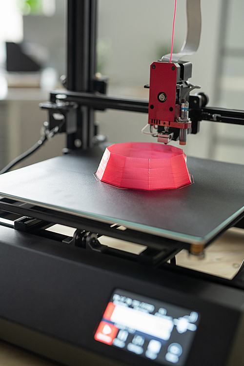 Printhead of 3d printer over part of pink round object on working surface during process of printing