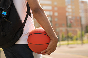 Young basketball player with ball and backpack standing on playground before outdoor training