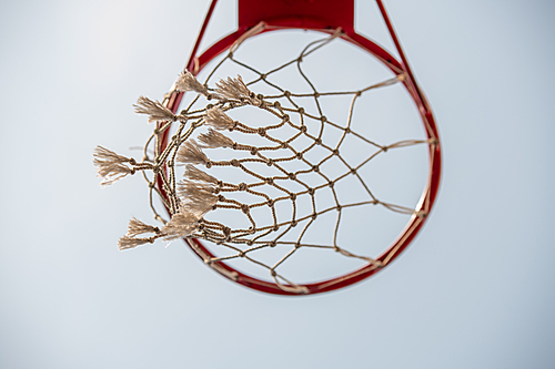 Below view of basket for playing basketball on background of light blue cloudless sky