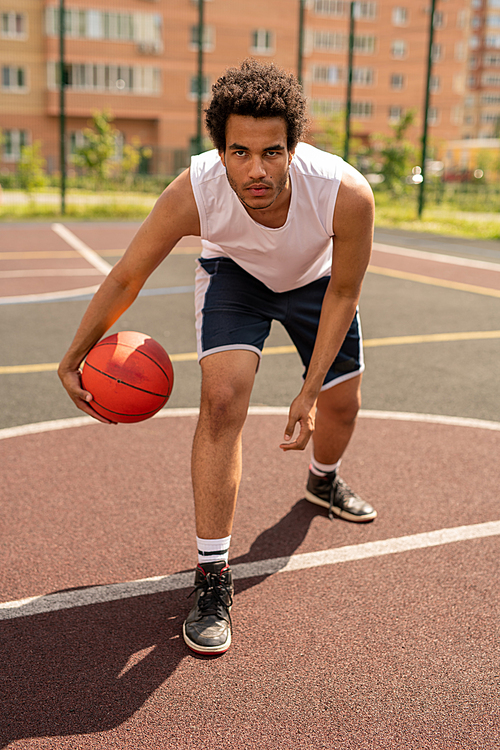 Serious young basketball player going to throw ball while standing by white line on the court