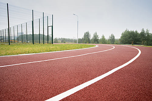 white dividing line making up race tracks in diminishing perspective on outdoor stadium in natural