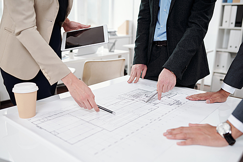Closeup of business team pointing at plans and drafts while discussing engineering project during meeting in office, copy space