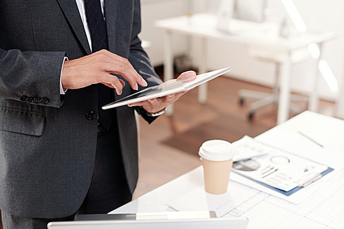 Cropped shot of unrecognizable successful businessman holding digital tablet over workplace, copy space background