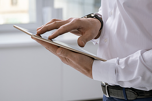 Hands of elegant businessman with tablet scrolling through online data while searching for something