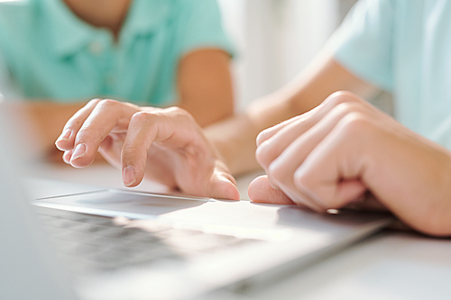 Hand of young woman or teenage girl over keypad of laptop before pressing one to enter website or online page