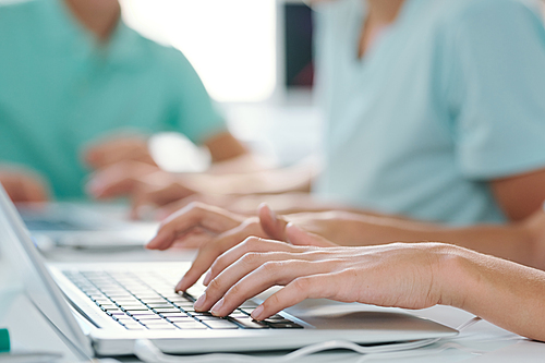 Hands of young female or schoolgirl over keypad of laptop during work over project or presentation