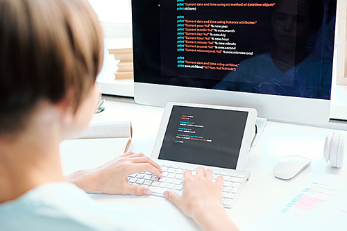 Human hands typing on desktop computer keypad in front of monitor and digital tablet with data