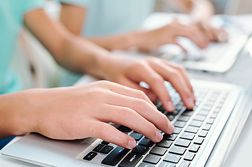 Hands of student or young manager pressing keys of laptop keypad while working over project