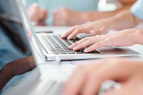 Hands of schoolkid or business person touching keys of laptop keypad while working with online data