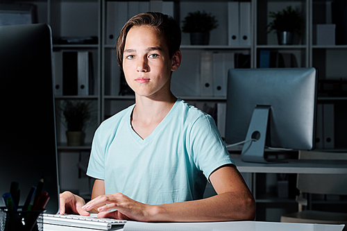 Successful and diligent student of middle school looking at you while working late over school project after classes