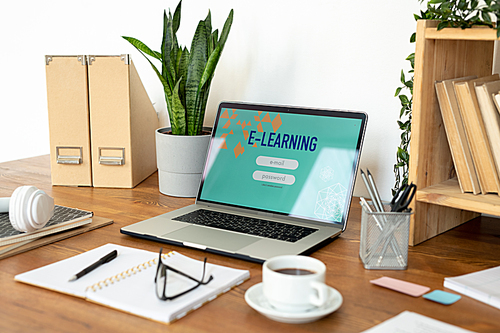 Laptop with website homepage on display surrounded by other office supplies and objects on the desk