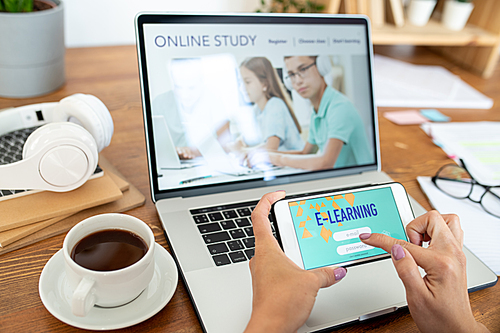 Human hands with smartphone signing in educational website while sitting in front of laptop display